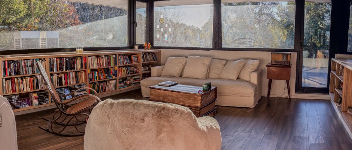 Living luminoso con biblioteca y vista al parque en una casa de country preparada para la venta
